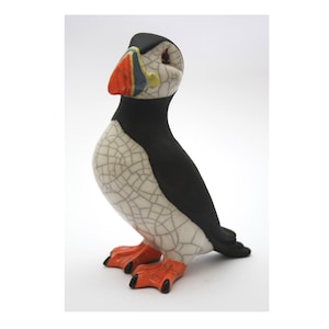 May include: A ceramic figurine of a puffin with a black head and back, white body with a crackled glaze, and orange beak and feet.