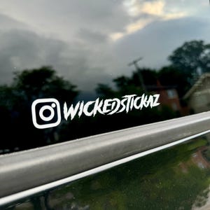 May include: A white vinyl sticker with the Instagram logo and the text "WICKEDSTICKAZ" on a black car window.