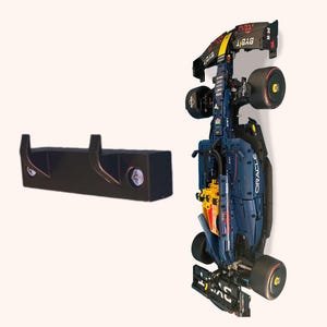 May include: A black wall mount with two hooks for hanging a Lego Formula 1 race car. The car is blue, yellow, and red with the Oracle logo and the words "Red Bull" on the side.