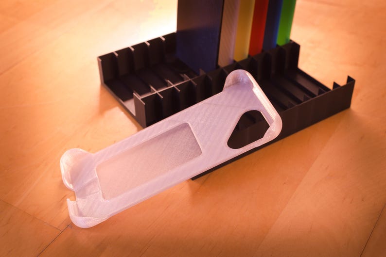 Op de afbeelding: Een witte plastic telefoonhoes met een textuur. De hoes is ontworpen om te passen op een smartphone en heeft een uitsparing voor de camera.