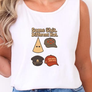 Puede incluir: Camiseta sin mangas blanca con el texto "Same Shit. Different Hat." e ilustraciones de cuatro sombreros: una capucha puntiaguda, una gorra de béisbol con la bandera confederada, una gorra militar con una calavera y una gorra roja "Make America Great Again".