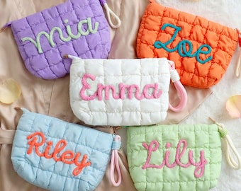 May include: Five quilted cosmetic bags in various colors: purple, orange, white, blue, and green. Each bag features a different name embroidered in a contrasting color. The bags have a wrist strap and a zipper closure.