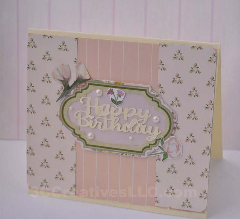 4 x 5.5 inch card in Peach floral and striped printed paper. Happy Birthday cutout in center  decorated with fussy cut flowers and white pearls .