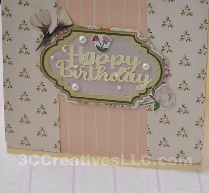 4 x 5.5 inch card in Peach floral and striped printed paper. Happy Birthday cutout in center  decorated with fussy cut flowers and white pearls .