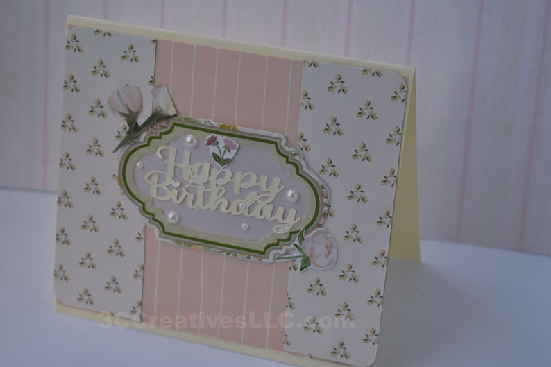 4 x 5.5 inch card in Peach floral and striped printed paper. Happy Birthday cutout in center  decorated with fussy cut flowers and white pearls .