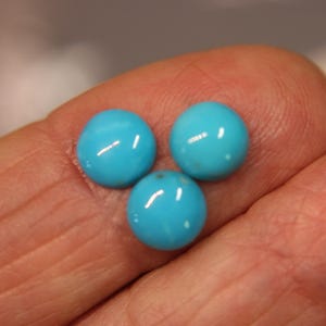 May include: Three small, round, cabochon-cut turquoise gemstones with a smooth, polished surface and a vibrant sky-blue colour. Each stone features a domed top and a flat base, displaying a consistent, bright blue hue with subtle natural variations.