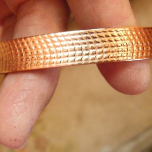 May include: A copper bracelet with a textured, hammered finish.