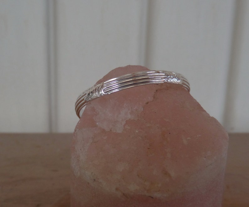 Pode incluir: Um anel de prata com um design texturizado, descansando sobre uma rocha rosa.