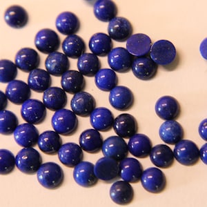 May include: A collection of round, dark blue lapis lazuli cabochons. The cabochons are smooth and polished, with a slight sparkle.
