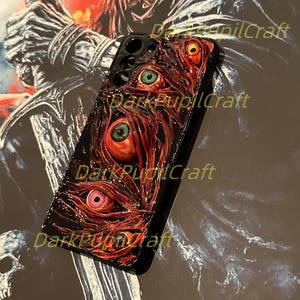 Puede incluir: Carcasa de tel&eacute;fono negra con un dise&ntilde;o rojo, blanco y negro con varios ojos. El texto "Dark Pupil Craft" es visible en la carcasa.