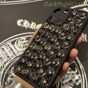 May include: Black phone case with a skull design. The case is covered in small, raised skulls.