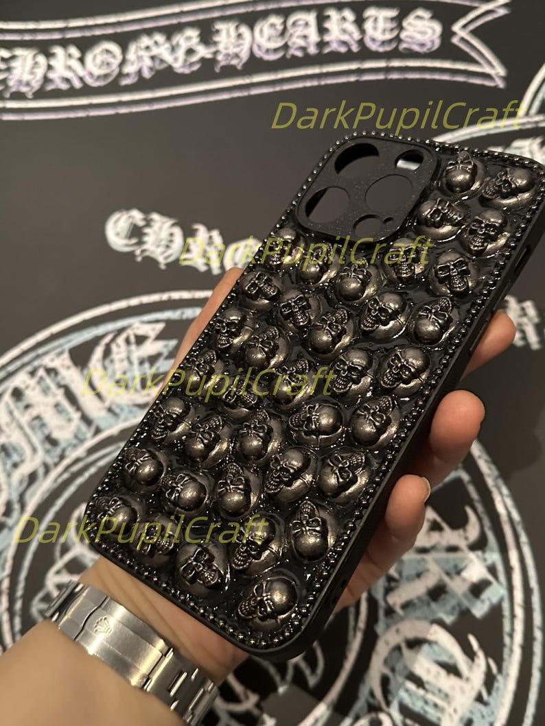 May include: Black phone case with a skull design. The case is covered in small, raised skulls.