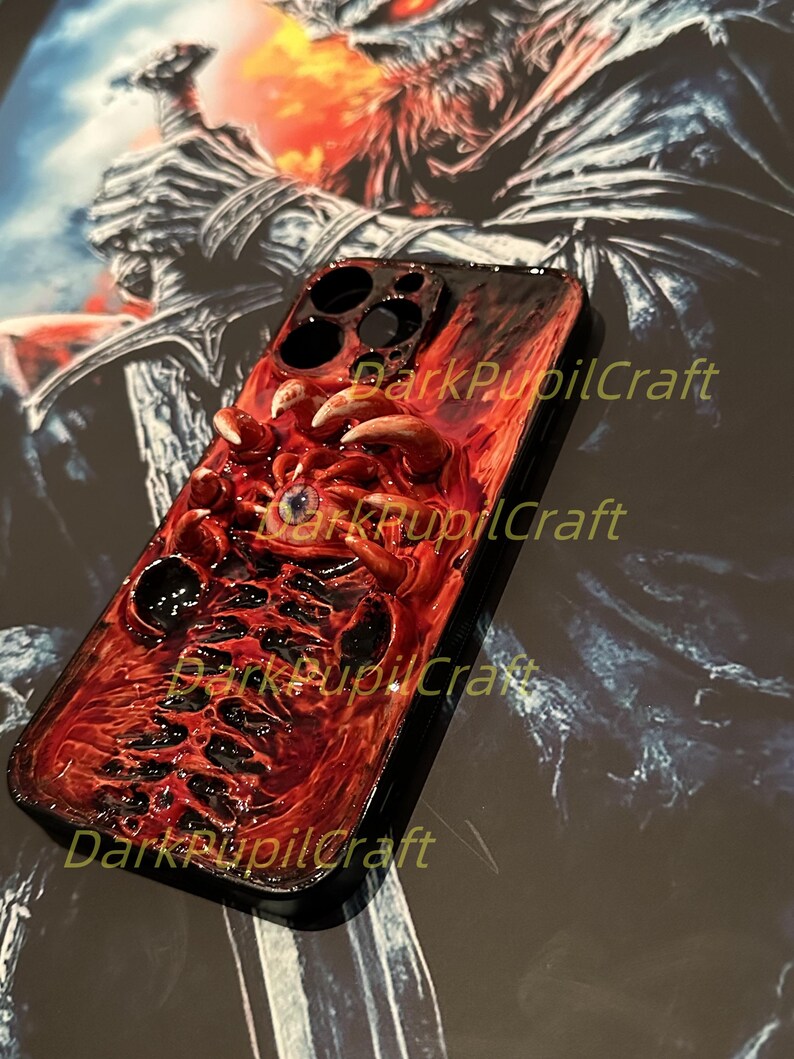 May include: A red and black iPhone case with a 3D sculpted design of a monstrous eye and tentacles. The case has the text "DarkPupilCraft" printed on it.