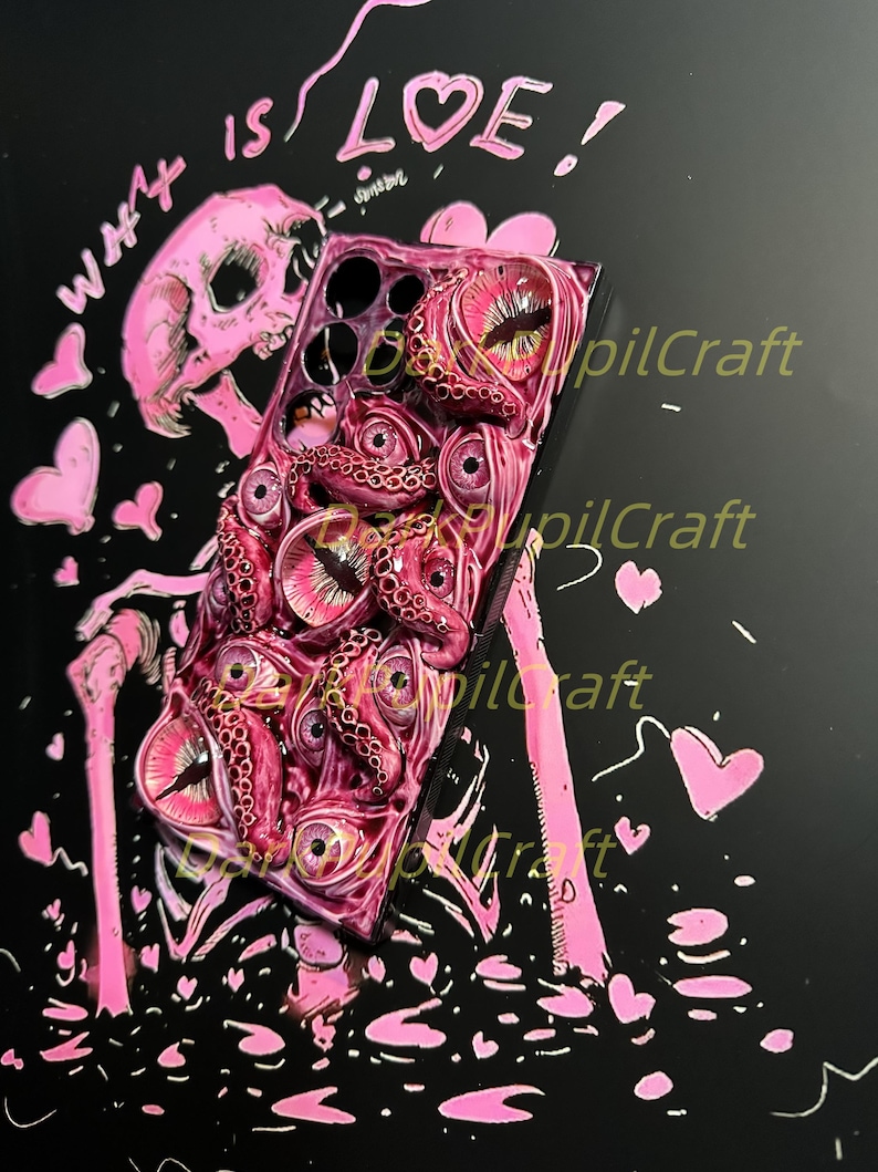 May include: A pink and black phone case with a skull and octopus design. The case has a textured surface and the text "What is Love!" is written on the top. The case is surrounded by pink hearts.