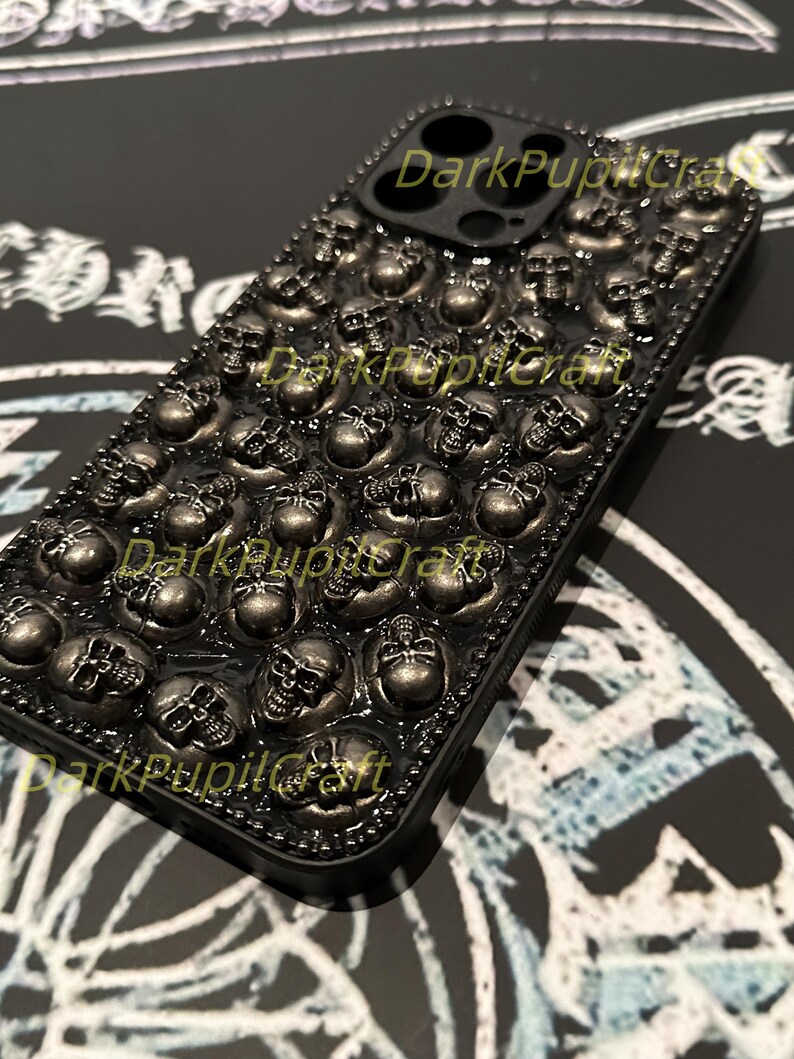 May include: Black phone case with a skull design. The case is covered in small, silver skulls.