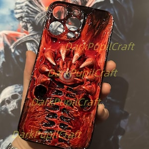 Puede incluir: Una funda para iPhone roja y negra con un diseño 3D detallado de un ojo monstruoso y garras. La funda tiene el texto "DarkPupilCraft" impreso en ella.