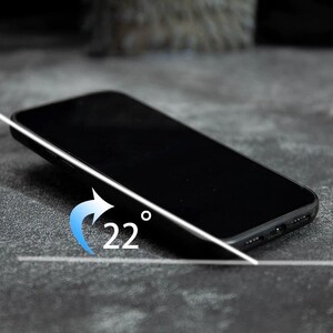 May include: A black smartphone positioned at a 22-degree angle, featuring a sleek frame with visible speaker grilles and a charging port at the bottom edge. A blue arrow graphic indicates the tilt angle with the text 22 degrees displayed.