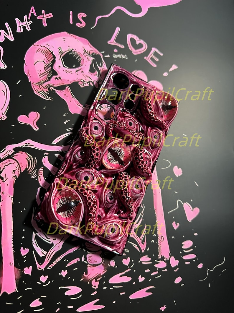 May include: A black phone case with a 3D design of pink and red tentacles and eyes. The case has the text "Dark Popcraft" printed on it.