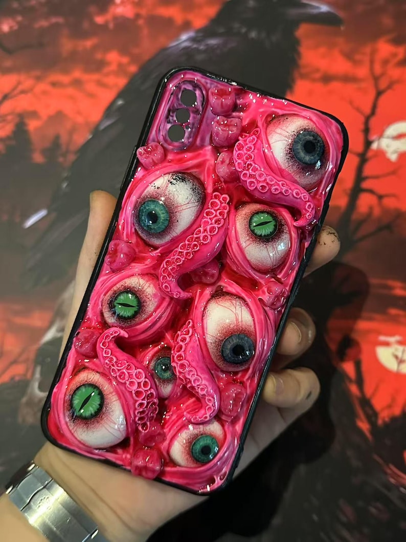 Op de afbeelding: Een roze telefoonhoesje met meerdere realistische oogballen met blauwe en groene irissen en roze tentakels. De hoes heeft een zwarte rand.