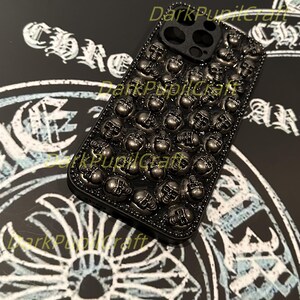 May include: Black phone case with a skull design. The case is covered in small, silver skulls.