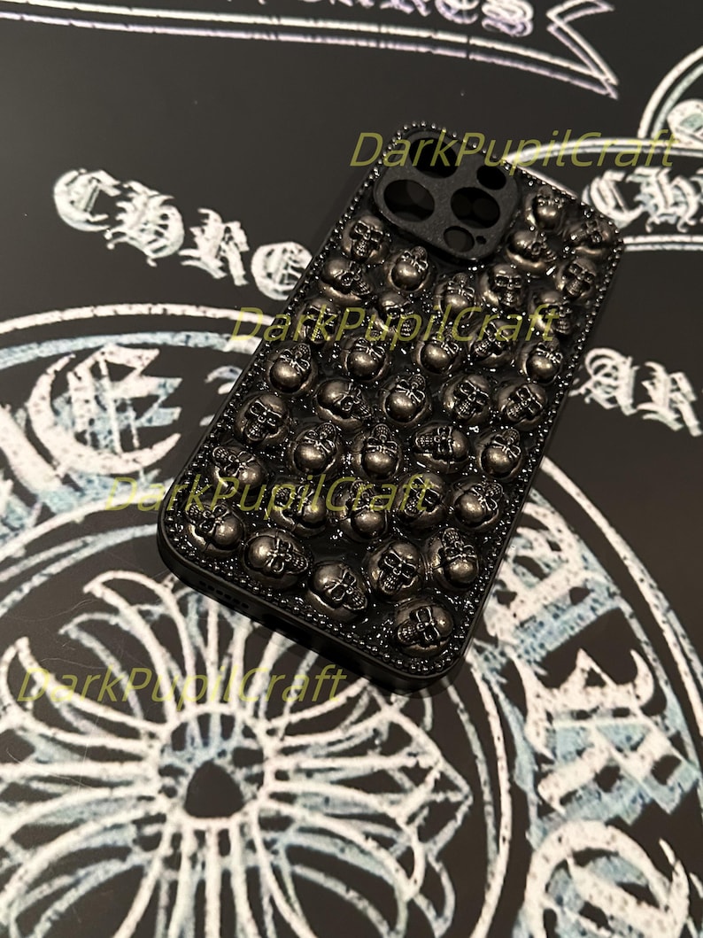 May include: Black phone case with a skull design. The case is covered in small, silver skulls.