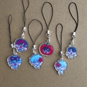 May include: A collection of acrylic charms with black lanyards. The charms feature cartoon characters with blue, pink, and red hair. One charm is a red apple with a character's face.
