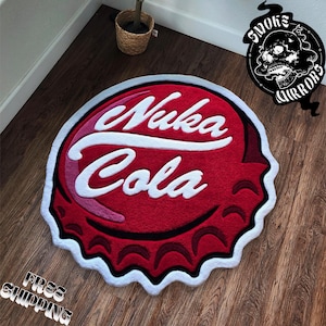 Puede incluir: Una alfombra roja, blanca y rosa con forma de tapón de botella de Nuka Cola. La alfombra presenta las palabras "Nuka Cola" en letras blancas estilizadas. La alfombra tiene un borde blanco y está sobre un suelo de madera.