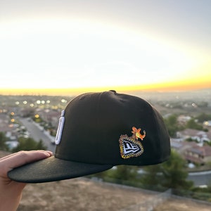 May include: A set of three ceramic mugs with a speckled, matte finish. The mugs are in shades of cream, light gray, and dark gray. Each mug has a simple, minimalist design and a rounded handle. The mugs are stacked on top of each other.