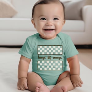 May include: A baby wearing a light blue bodysuit with a brown checkered pattern and the text "hugs & snugs".