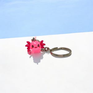 Looking for a cheerful accessory that makes every day brighter? This Mini Axolotl Keychain is the answer! Its happy little expression adds a splash of joy to your keys, bag, or backpack. The perfect token for animal lovers, aquarium fans, or anyone who loves tiny handmade treasures.