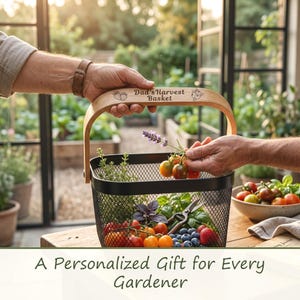 Op de afbeelding: Een zwarte metalen gaas mand met een lichthouten handvat gegraveerd met de tekst Dad's Harvest Basket, voorzien van illustraties van aardbeien en bosbessen, gevuld met verse tuinproducten zoals tomaten, kruiden en bessen.