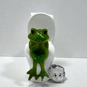 This whimsical frog on toilet figurine brings charm and comedy to any space. Perfect as funny bathroom decor or a novelty shelf accent, it’s a popular silly frog gift for friends and coworkers. Ideal for frog collectors, gift baskets, and anyone who appreciates lighthearted home decor.