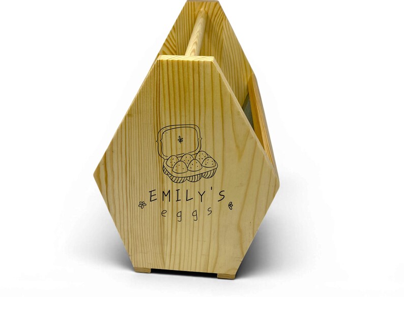 A clean studio photograph shows the handcrafted pine basket with its custom laser engraved front panel, breathable wire mesh sides and rounded dowel handle. This personalized egg collection basket is a handmade farmhouse egg gathering basket, a solid pine wood egg and produce basket with breathable metal mesh sides, a smooth sanded dowel carry handle, and a laser engraved front panel, about 12 inches long, 7.5 inches wide and 10 inches tall. A custom chicken egg basket, engraved egg holder...