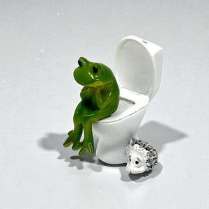 This funny frog on toilet figurine is the perfect blend of cute and silly bathroom decor. Designed to spark laughs instantly, this whimsical frog statue makes a great gag gift, stocking stuffer, or novelty home accent. Ideal for frog lovers, funny gift collectors, and anyone who enjoys playful bathroom humor. A small but unforgettable conversation-starting frog figurine.