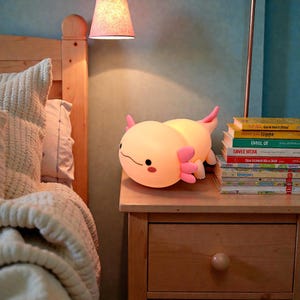 Cute meets comfort with this pink squishy axolotl night light, designed to help kids feel secure at night. The soft silicone body is safe to touch, and the gentle LED lighting offers three adjustable settings for the perfect glow. With a timer feature for hands-free use, this axolotl lamp is ideal for nurseries, kids’ rooms, and bedtime gifting.