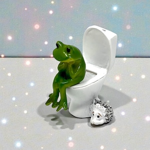 Bring playful humor to your home with this funny frog on toilet figurine. A favorite among frog lovers and gift shoppers, this novelty frog statue is ideal for funny bathroom decor, office humor, or quirky shelf displays. A small gift with big personality and lasting laughs.