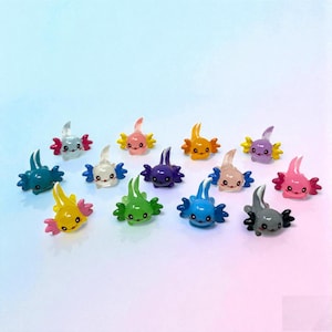May include: A collection of colorful axolotl figurines in various shades, including blue, green, yellow, pink, purple, and orange. Each figurine has a unique color combination and a smiling face. The axolotls are arranged on a gradient background.
