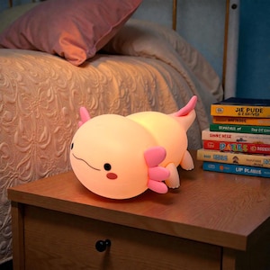 Create a peaceful sleep space with this pink axolotl LED night lamp for kids. The soft, squishy silicone body pairs perfectly with a warm, soothing glow that won’t strain young eyes. Choose between three lighting settings and activate the timer for automatic shutoff. This cute axolotl night light doubles as charming decor and a comforting bedtime companion.