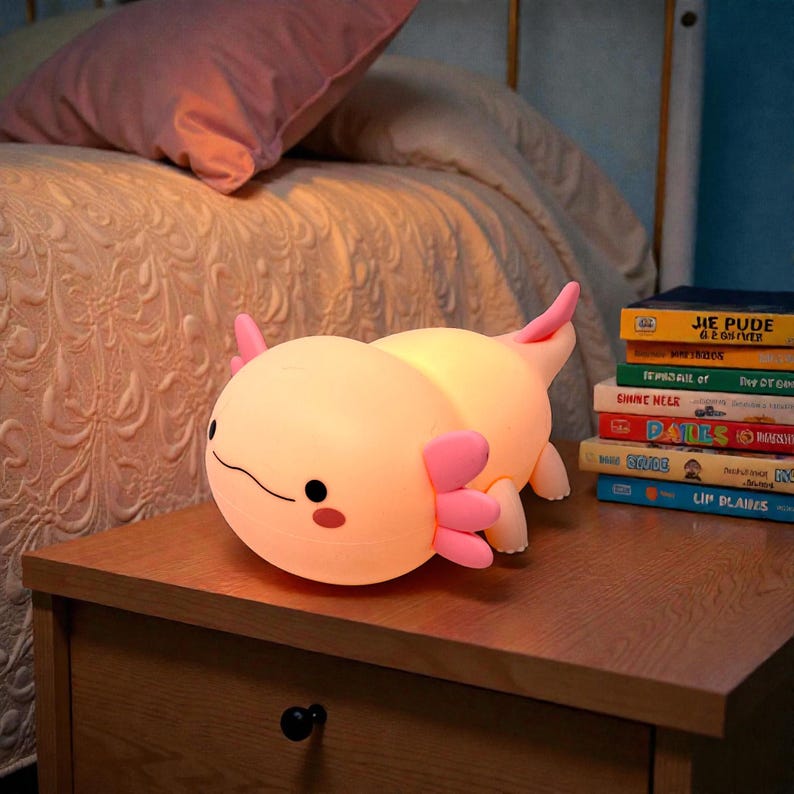 Create a peaceful sleep space with this pink axolotl LED night lamp for kids. The soft, squishy silicone body pairs perfectly with a warm, soothing glow that won’t strain young eyes. Choose between three lighting settings and activate the timer for automatic shutoff. This cute axolotl night light doubles as charming decor and a comforting bedtime companion.