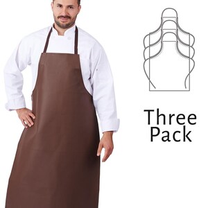 May include: A brown apron with a dark brown neck strap is worn over a white chef's coat. The image includes a diagram of the apron and the text "Three Pack". The apron is designed to protect clothing during food preparation.