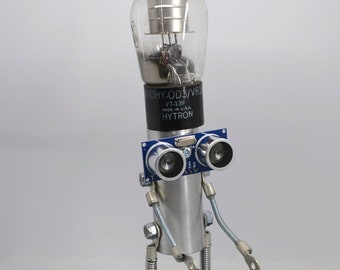 robot, bot, sculpture art assemblage figure created with found recycled materials old tube head  pipe and laser eyes