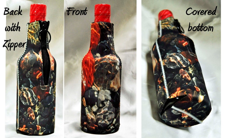 May include: A black and red bottle cooler with a zipper on the back. The cooler has a colorful abstract print. The bottom of the cooler is covered.