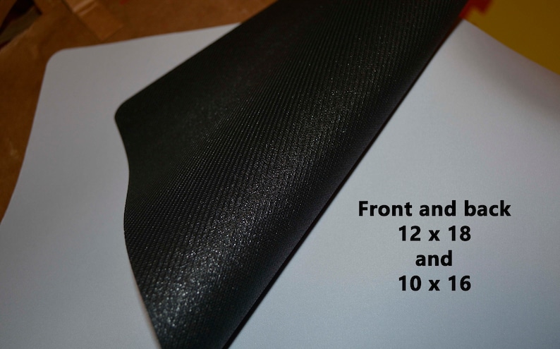 May include: A black mouse pad with a textured surface. The mouse pad is folded in half, revealing a white surface with the text "Front and back 12 x 18 and 10 x 16".
