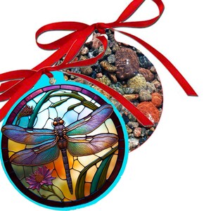 May include: A round, blue and turquoise Christmas ornament with a stained glass dragonfly design. The dragonfly has iridescent wings and a brown body. The ornament is tied with a red ribbon.