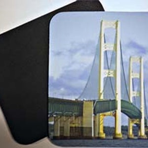 May include: A close-up view of the Mackinac Bridge in Michigan, with the bridge's white towers and suspension cables visible against a cloudy sky.