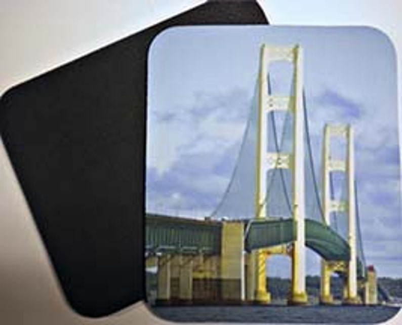 May include: A close-up view of the Mackinac Bridge in Michigan, with the bridge's white towers and suspension cables visible against a cloudy sky.