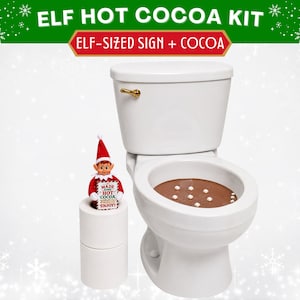 May include: An Elf Hot Cocoa Kit featuring a white toilet with brown liquid and white marshmallows inside the bowl. A small elf doll holds a sign that reads MADE SOME HOT COCOA ENJOY. The kit includes an elf-sized sign and cocoa components.