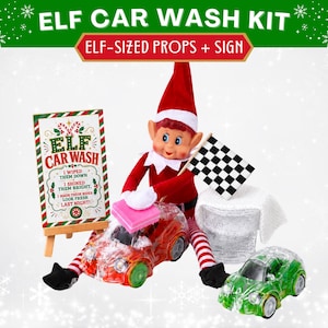 May include: An elf car wash kit featuring a sign that reads ELF CAR WASH, a red and white elf doll, a black and white checkered flag, a white textured cloth, and two small toy cars, one red and one green, with a gold circle badge labeled 16.