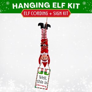 May include: A hanging elf kit featuring a red and white elf doll suspended upside down by brown and white cording. The elf wears a black belt and holds a rectangular white sign with green and red borders that reads, Well, this is Embarrassing.