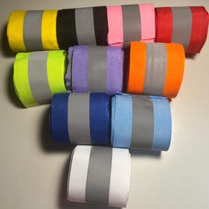 May include: Assortment of colorful ribbon rolls with reflective silver stripes. The ribbons are in various colors, including yellow, green, purple, orange, blue, white, red, black, and pink.